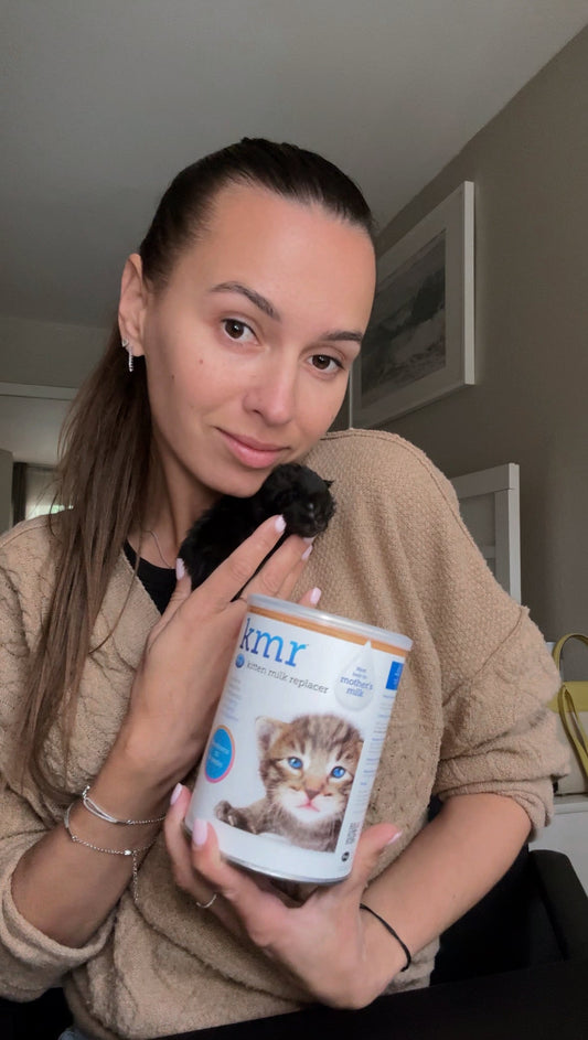Alyona holding a container of kitten milk replacer at home, sharing a story about saving a 5-day-old Maine Coon kitten